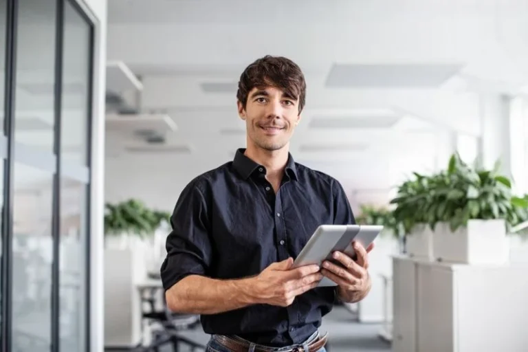 Confident Businessman Holding Digital Tablet While Standing In Creative Office Low Res